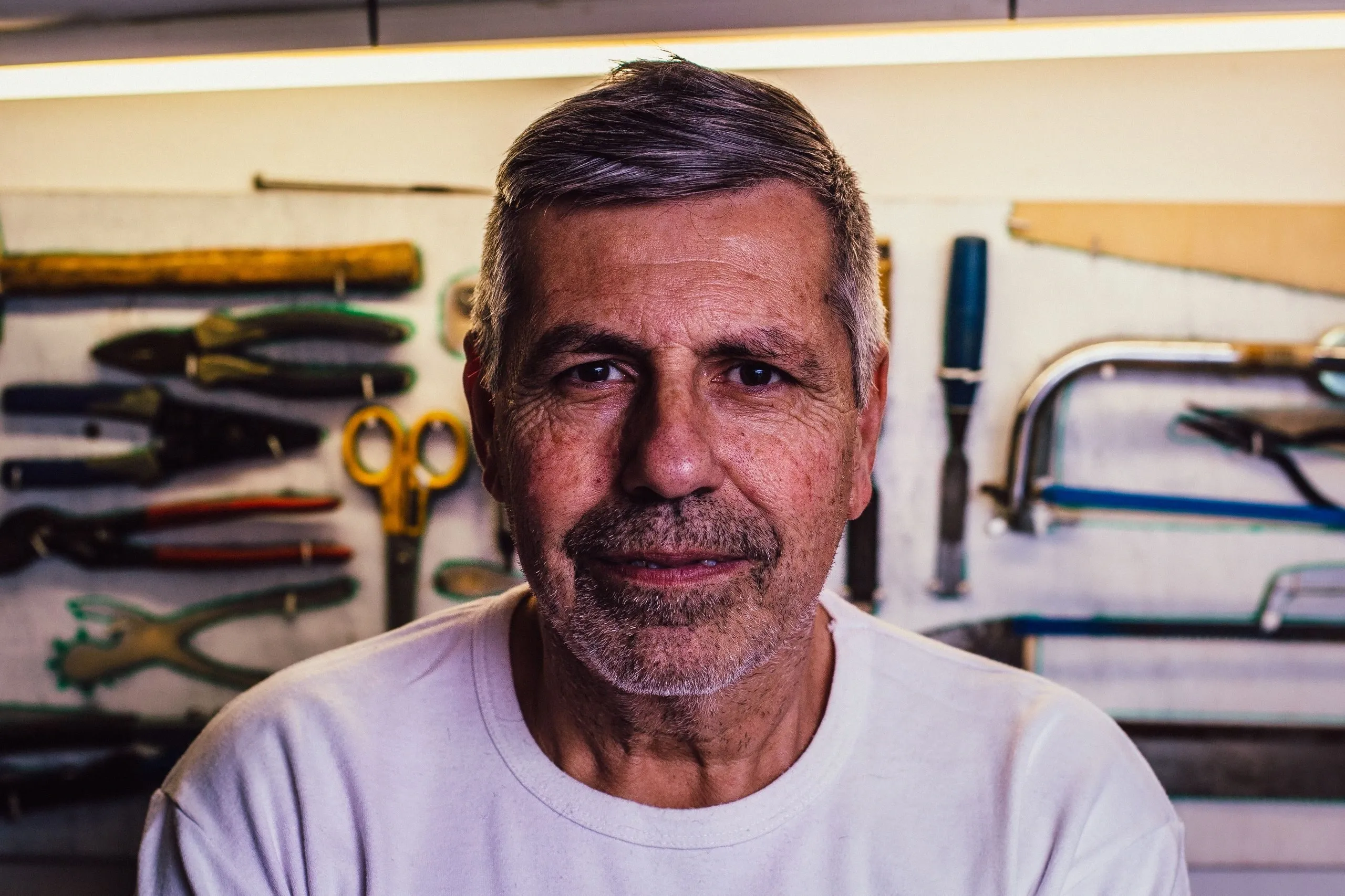 Bernard sourit devant le panneau d'outils de l'atelier