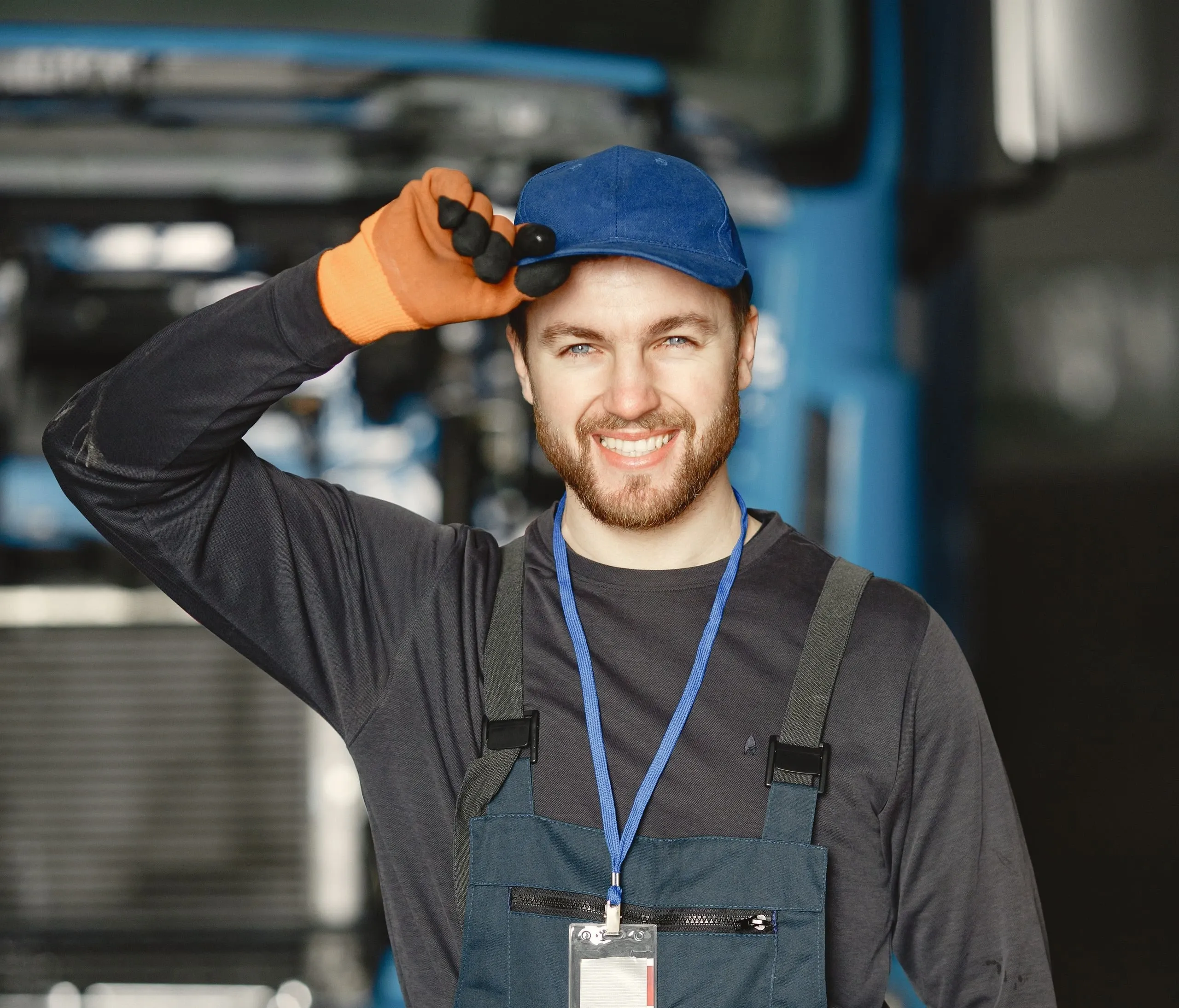 Mathis, en salopette et casquette bleue, salue en souriant