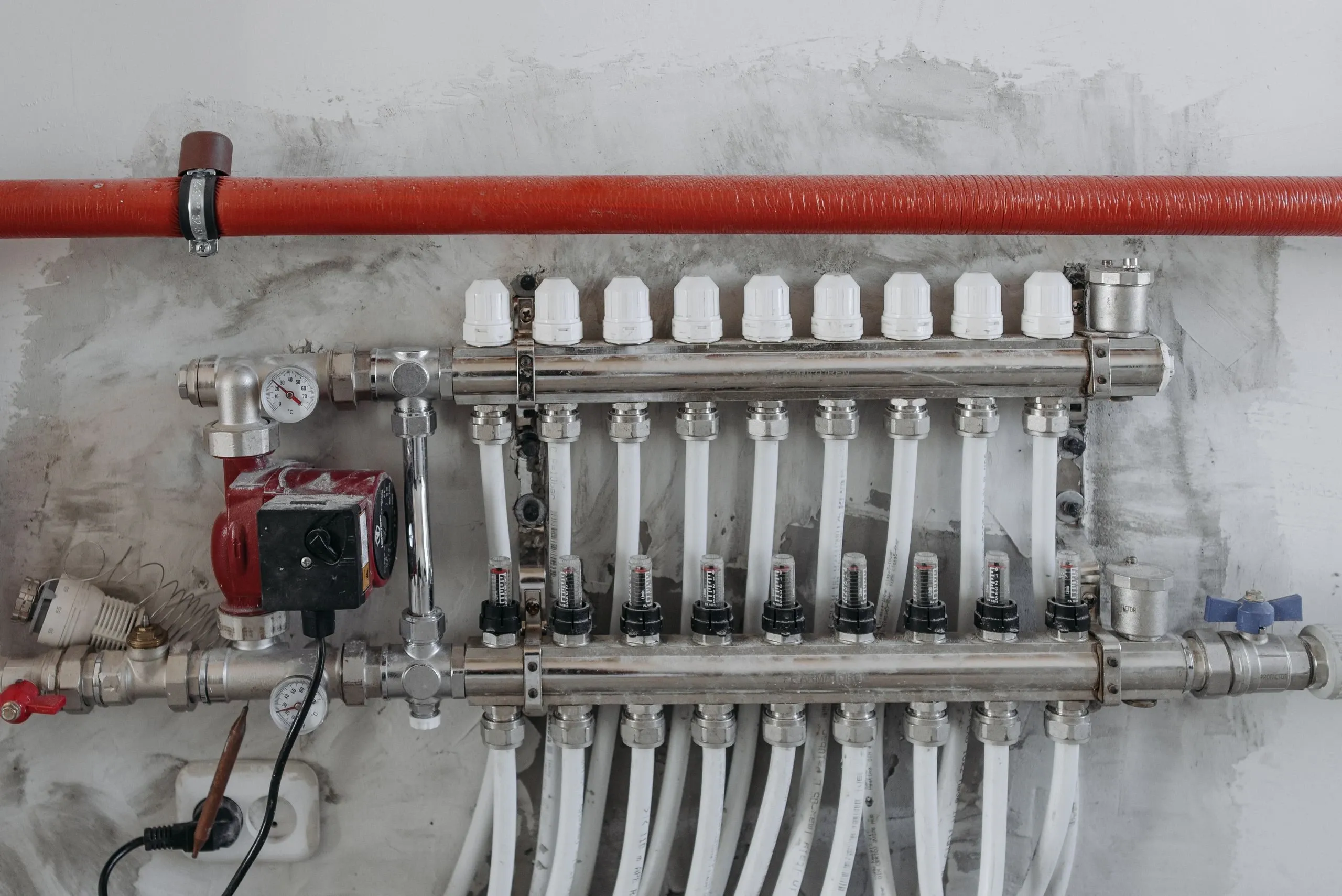 Le collecteur d'un plancher chauffant : vannes, débitmètres et tubes blancs
