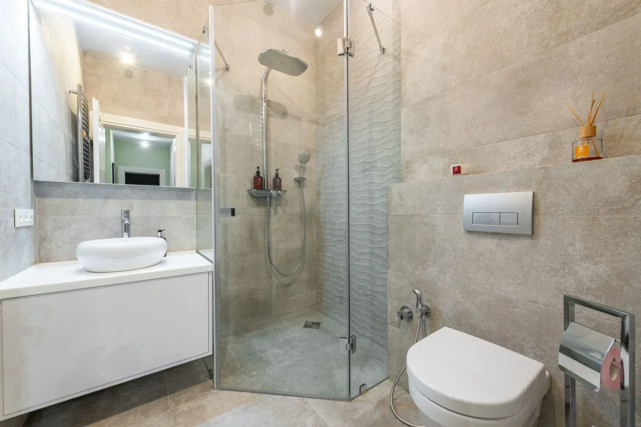 La salle de bains refaite : douche d'angle vitrée, vasque posée, WC suspendu
